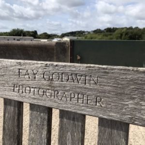 Close up photo of a wooden bench with the inscription "Fay Godwin, Photographer" in capital letters