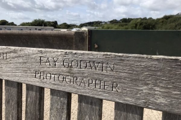 Close up photo of a wooden bench with the inscription "Fay Godwin, Photographer" in capital letters