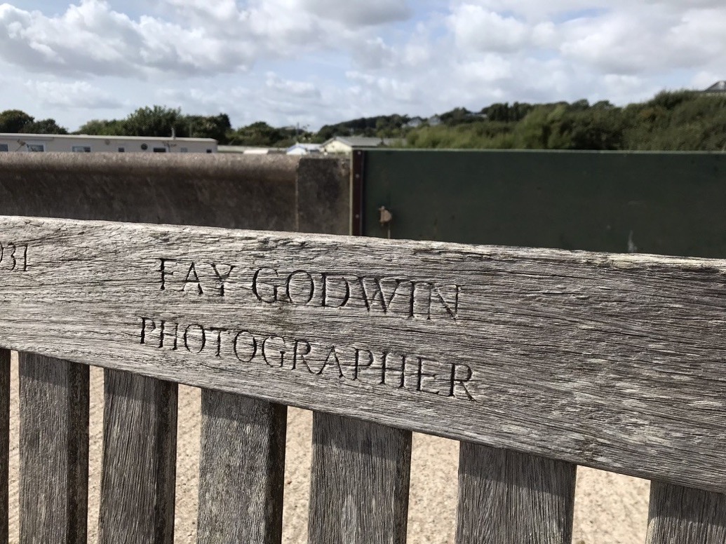 Close up photo of a wooden bench with the inscription "Fay Godwin, Photographer" in capital letters