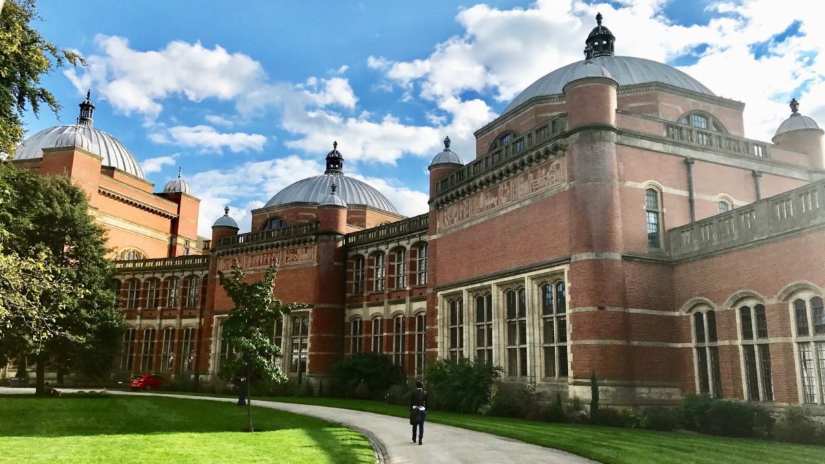 A landscape photograph of the red-bricked Aston Webb building slightly from one side. Two of the grey domes on the top of the building are in view.