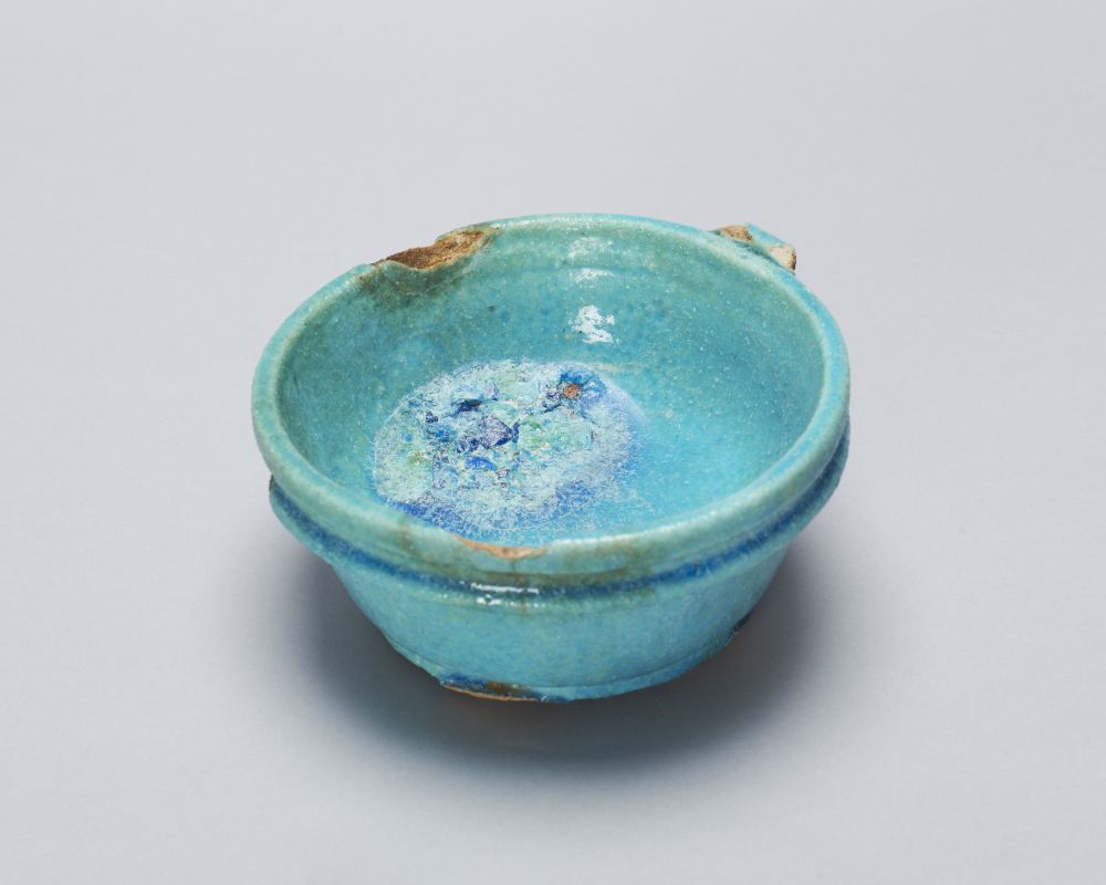 This Roman Period faience bowl, ECM 586, shows clear signs of manufacturer errors. The most distinct mistake is the pool of glaze inside the bowl.