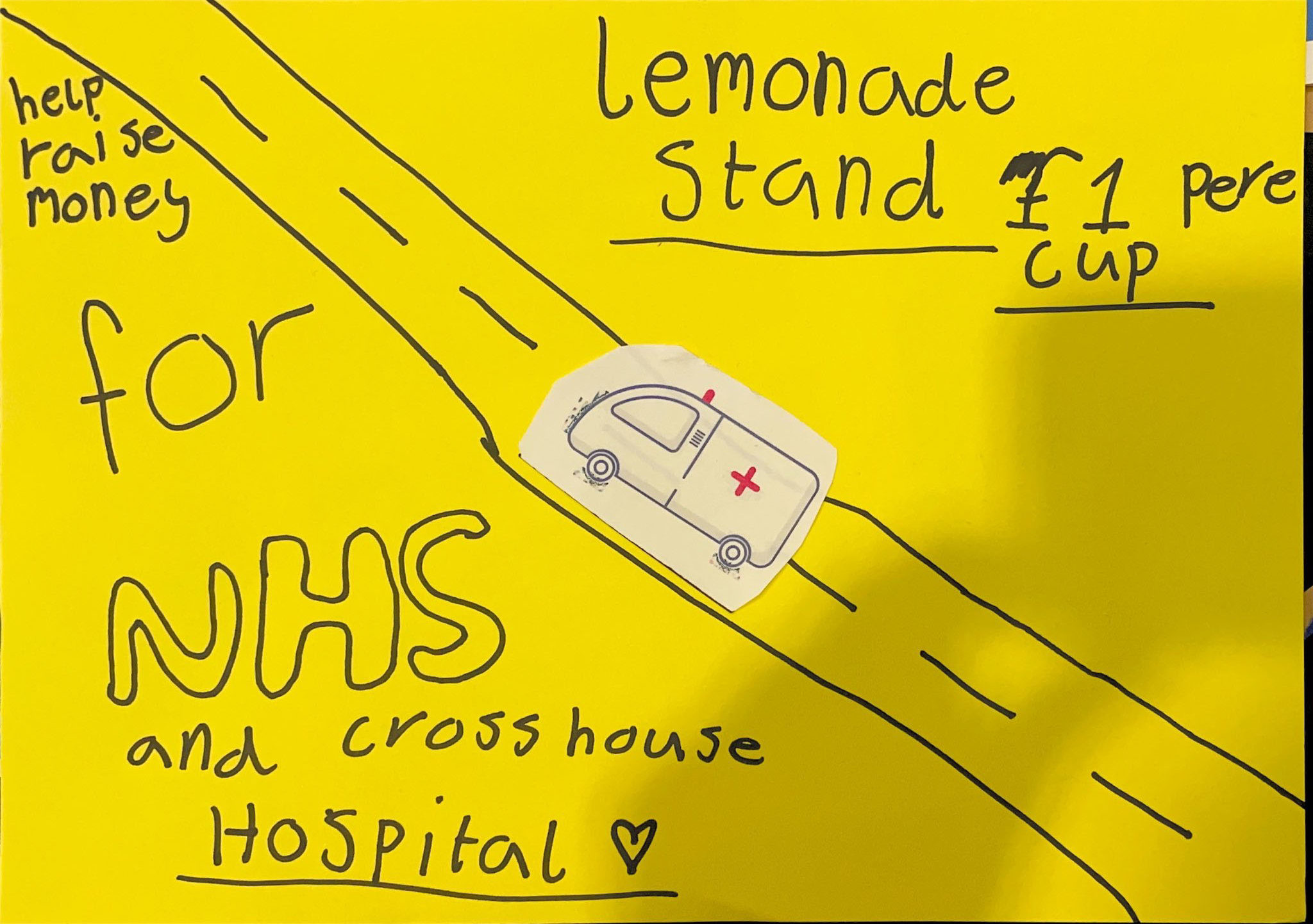 A poster with a bright yellow background features the text "Lemonade Stand £1 per cup" at the top. Diagonally across the poster is a drawing of a road with a cut-out image of a white ambulance driving on it. On the left side of the diagonal, the text reads, "Help raise money for NHS and Crosshouse Hospital," with "NHS" written in bubble font and a heart symbol next to an underlined "Hospital." The poster suggests hosting a lemonade stand to raise funds for the NHS and Crosshouse Hospital.