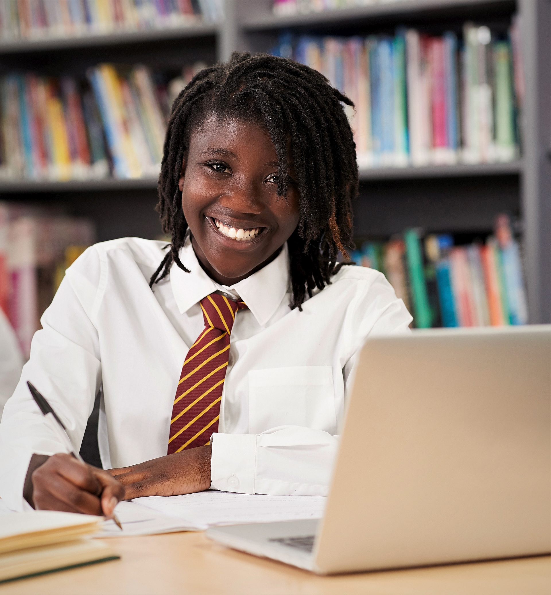 A smiling schoolgirl sits at a laptop