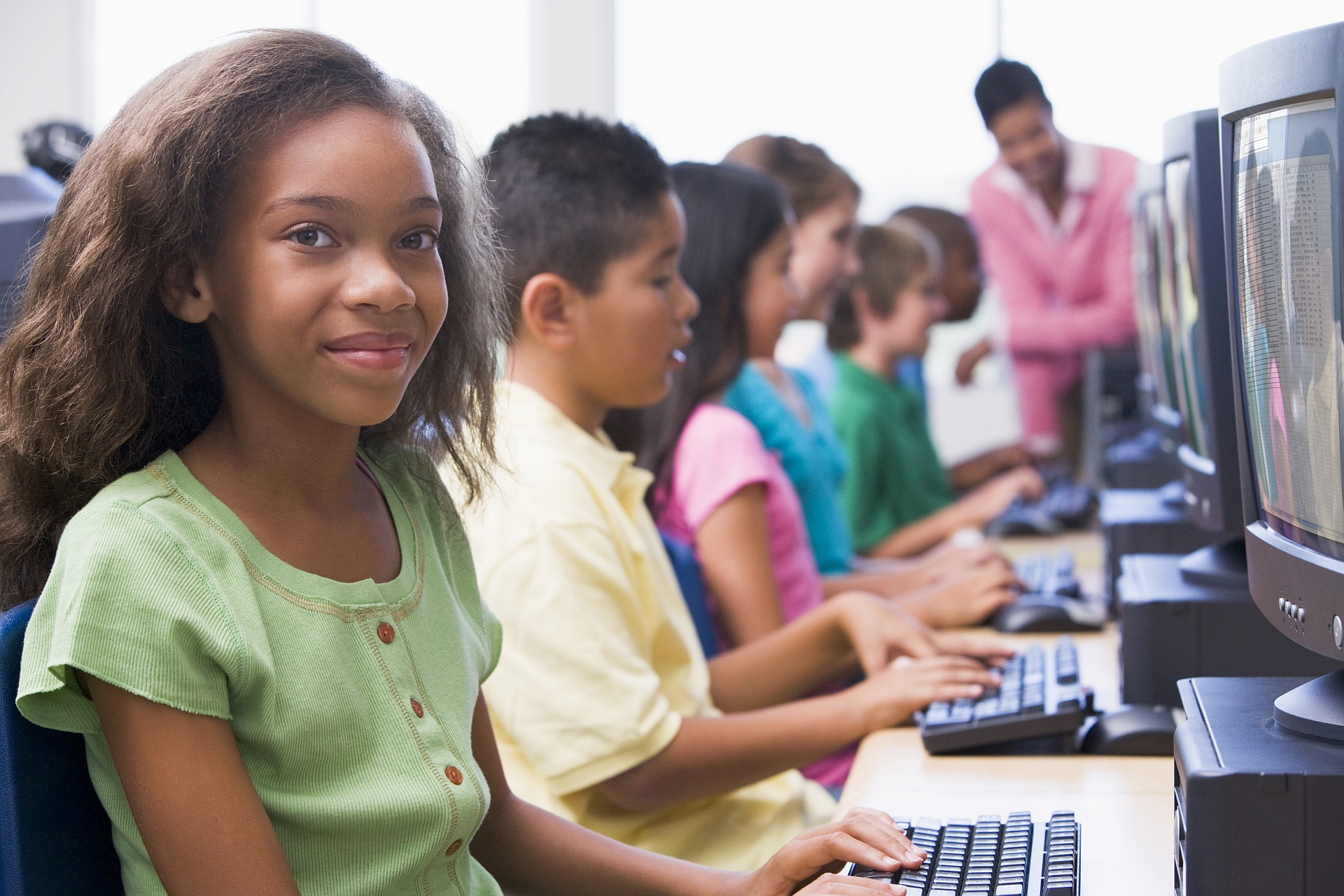 A smiling schoolgirl sits with a laptop