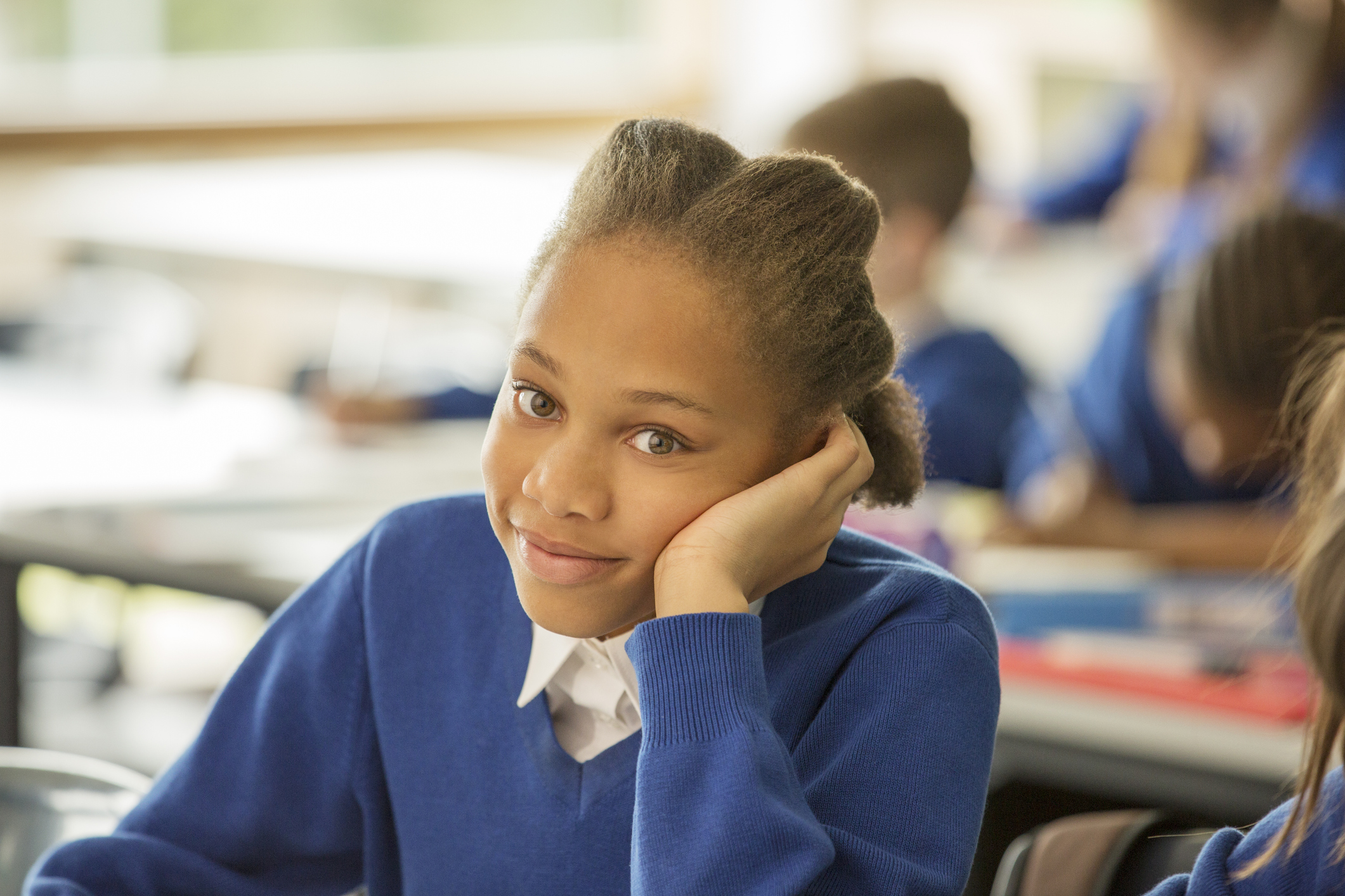 A smiling schoolgirl sits in a classroom