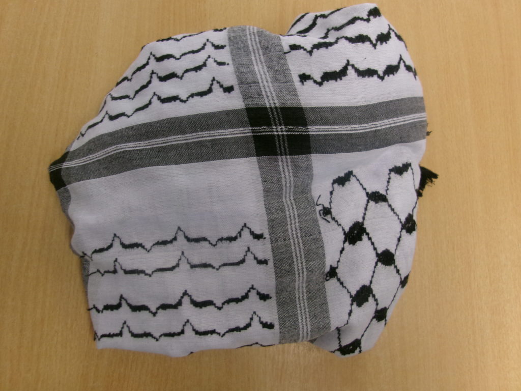 An image of a keffiyeh, folded to show its meaningful patterns and placed on a classroom desk